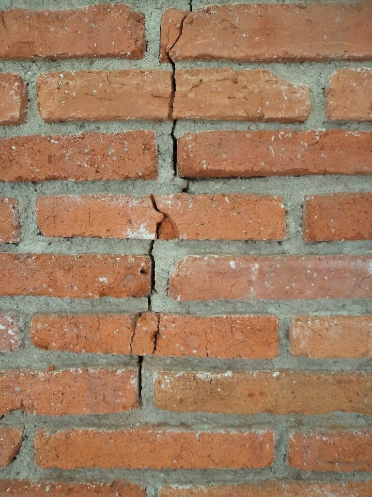 Close-up of a vertical crack running through a brick wall