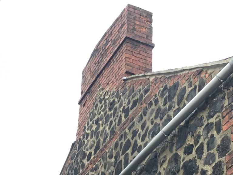 Aerial view of a damaged chimney stack with spalled brickwork